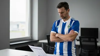 A frustrated Werder Bremen coach in his mid-40s, with short dark hair and a stern expression, standing in a blue and...