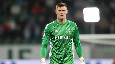A photorealistic image of a 25-30 year old, 1.85m tall, Werder Bremen goalkeeper, wearing a green and white jersey, with...